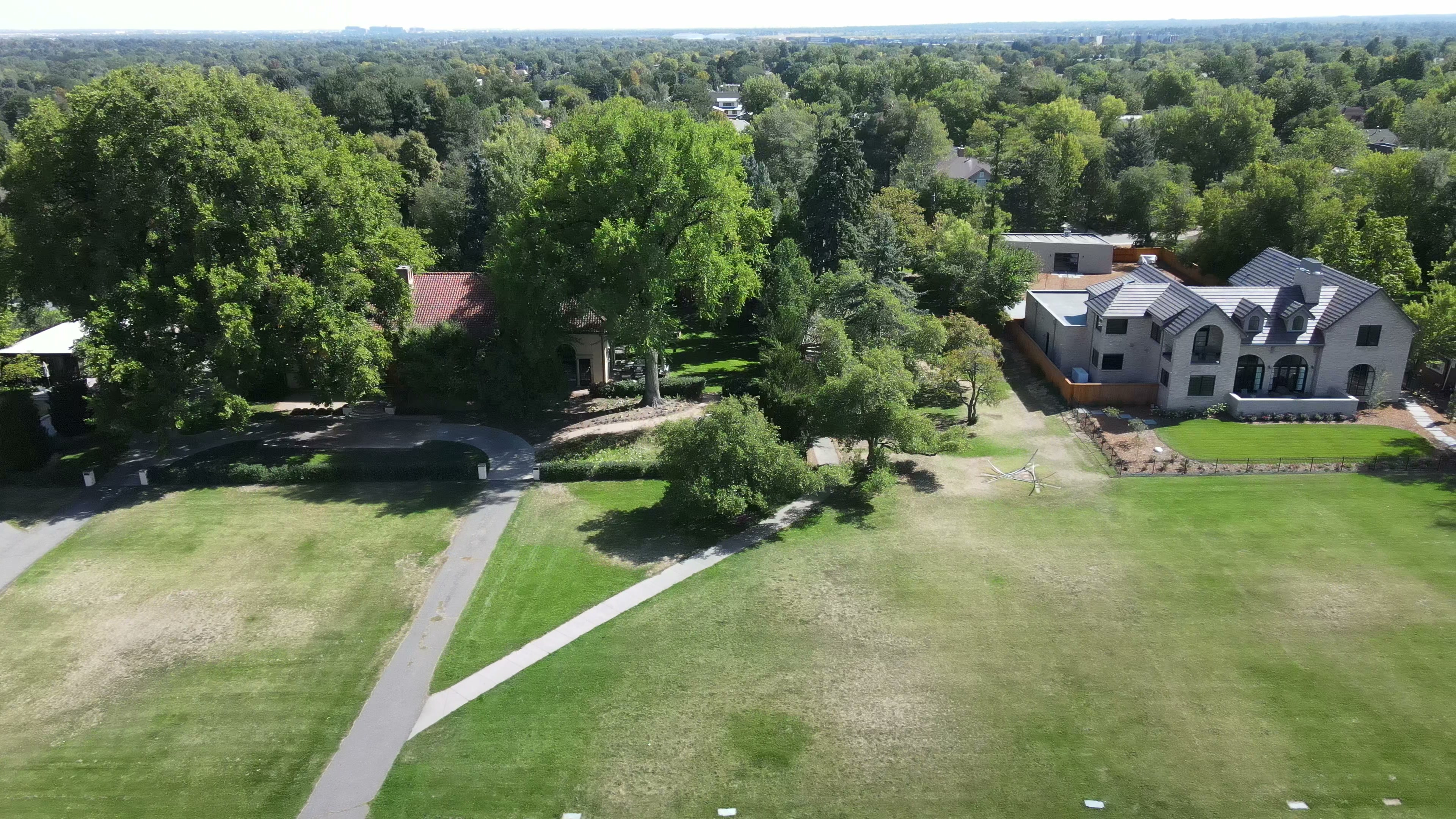 Aerial drone view of Denver Hilltop neighborhood — large-lot estate homes bordering park greenspace with sweeping mature tree canopy