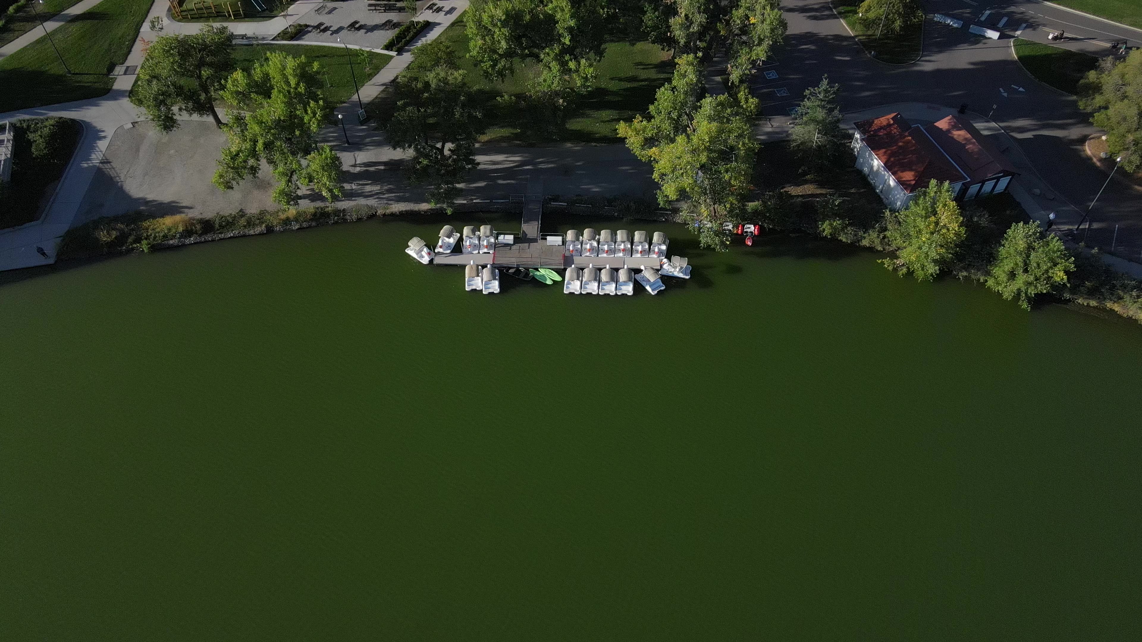 Aerial view directly above the swan-paddleboat dock at Smith Lake, Washington Park, Denver, with the historic boathouse alongside.