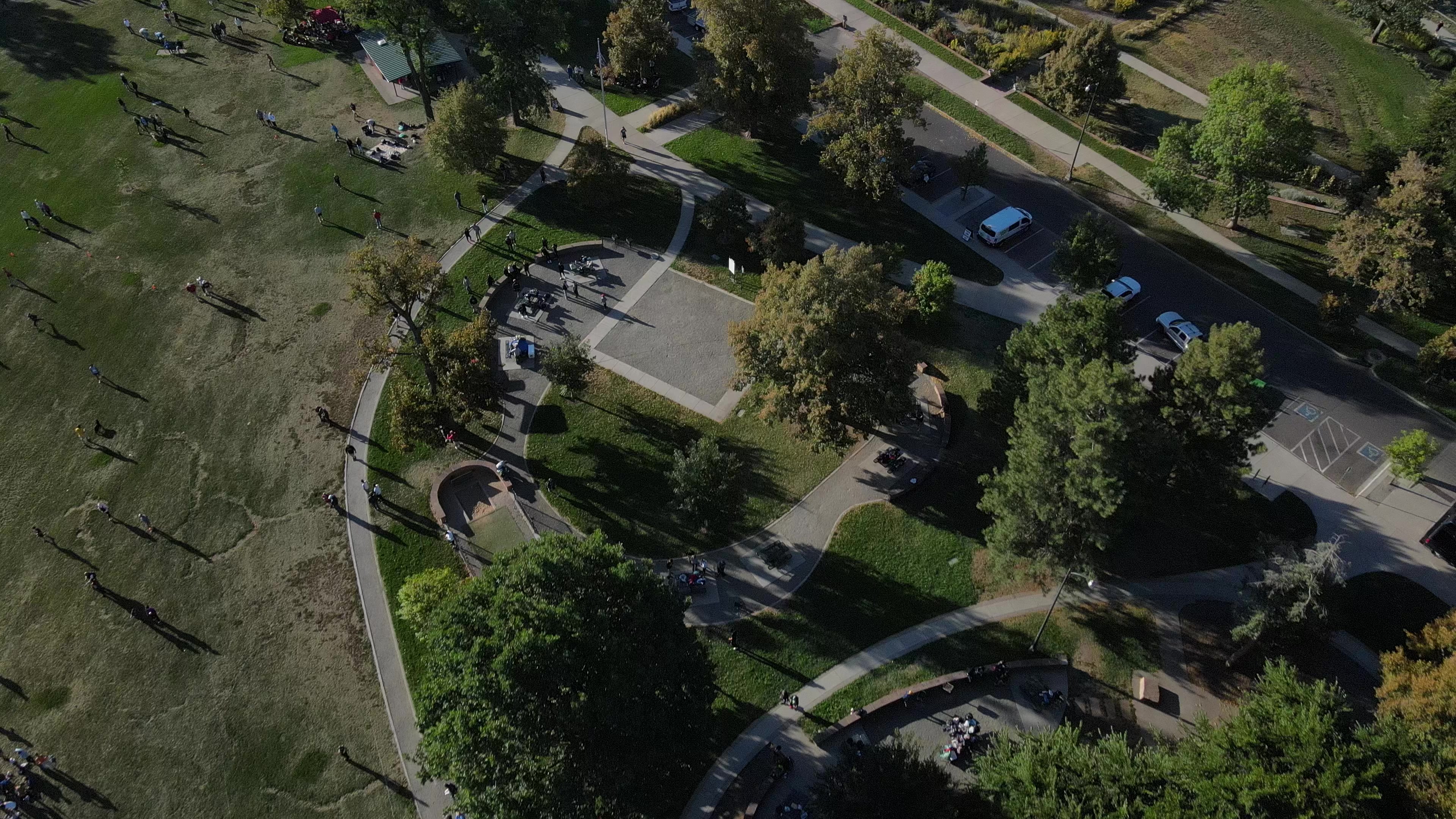 Aerial over the tree-lined paths and lawns of Washington Park, Denver, in late-afternoon light.